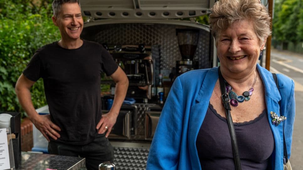 Two residents laughing beside a van