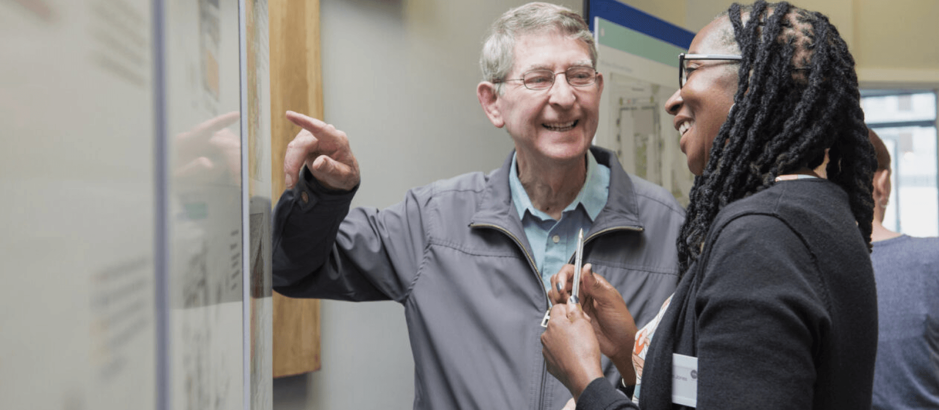 Two people looking at a whiteboard, chatting and smiling